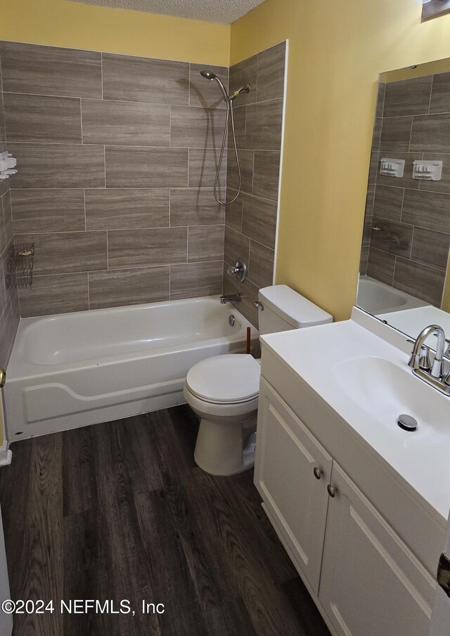 full bathroom featuring toilet, hardwood / wood-style floors, tiled shower / bath combo, and vanity