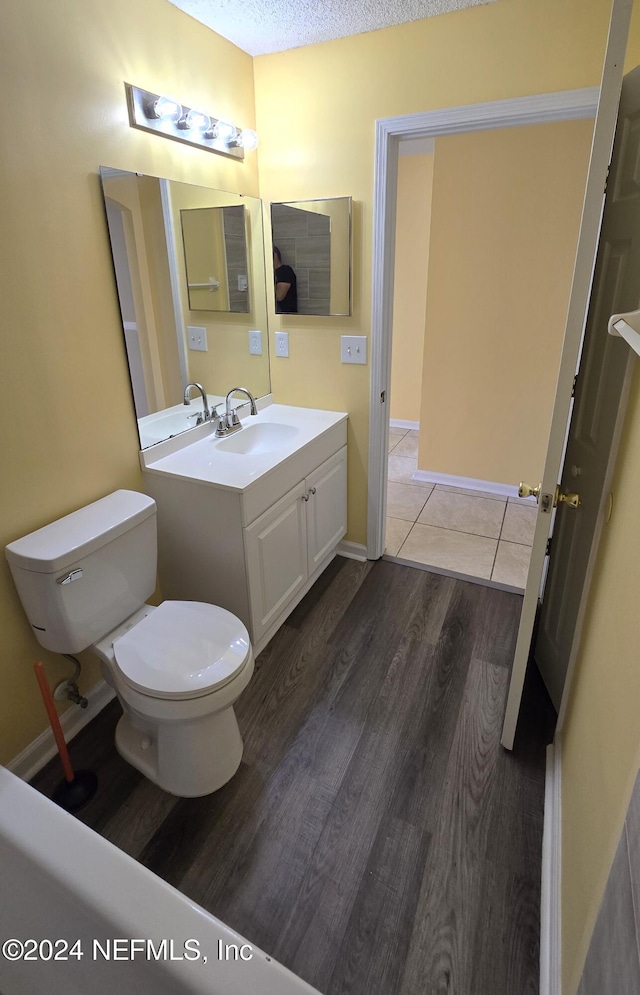 bathroom with vanity, a textured ceiling, hardwood / wood-style flooring, and toilet