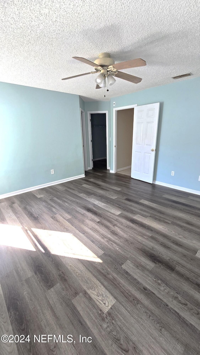 empty room with dark wood-type flooring, ceiling fan, and a textured ceiling