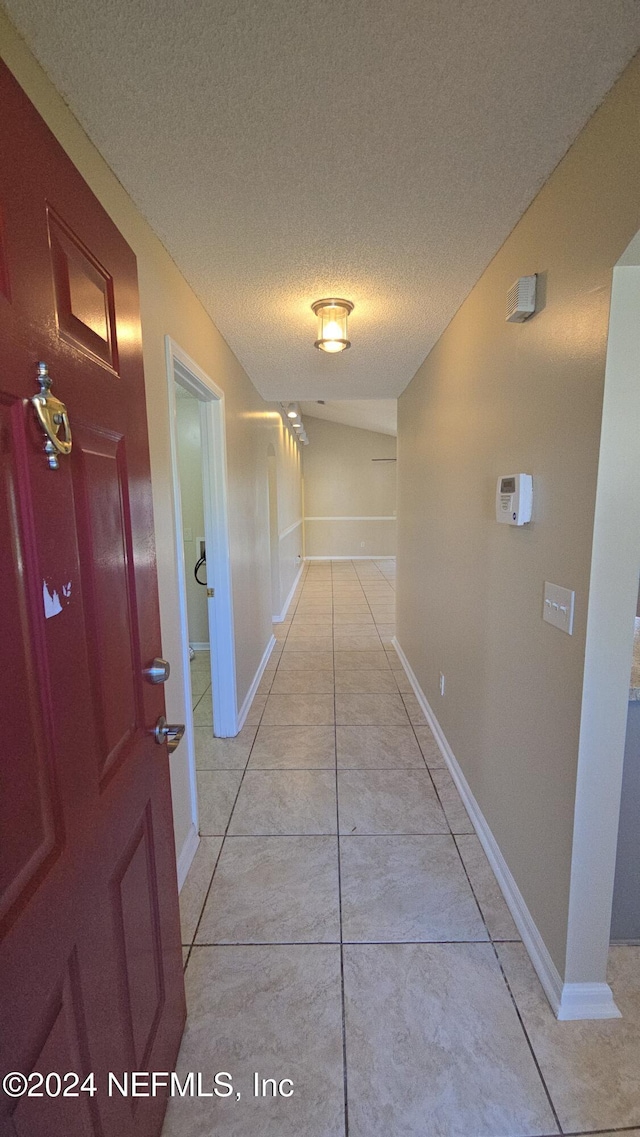 hall featuring a textured ceiling and light tile patterned floors