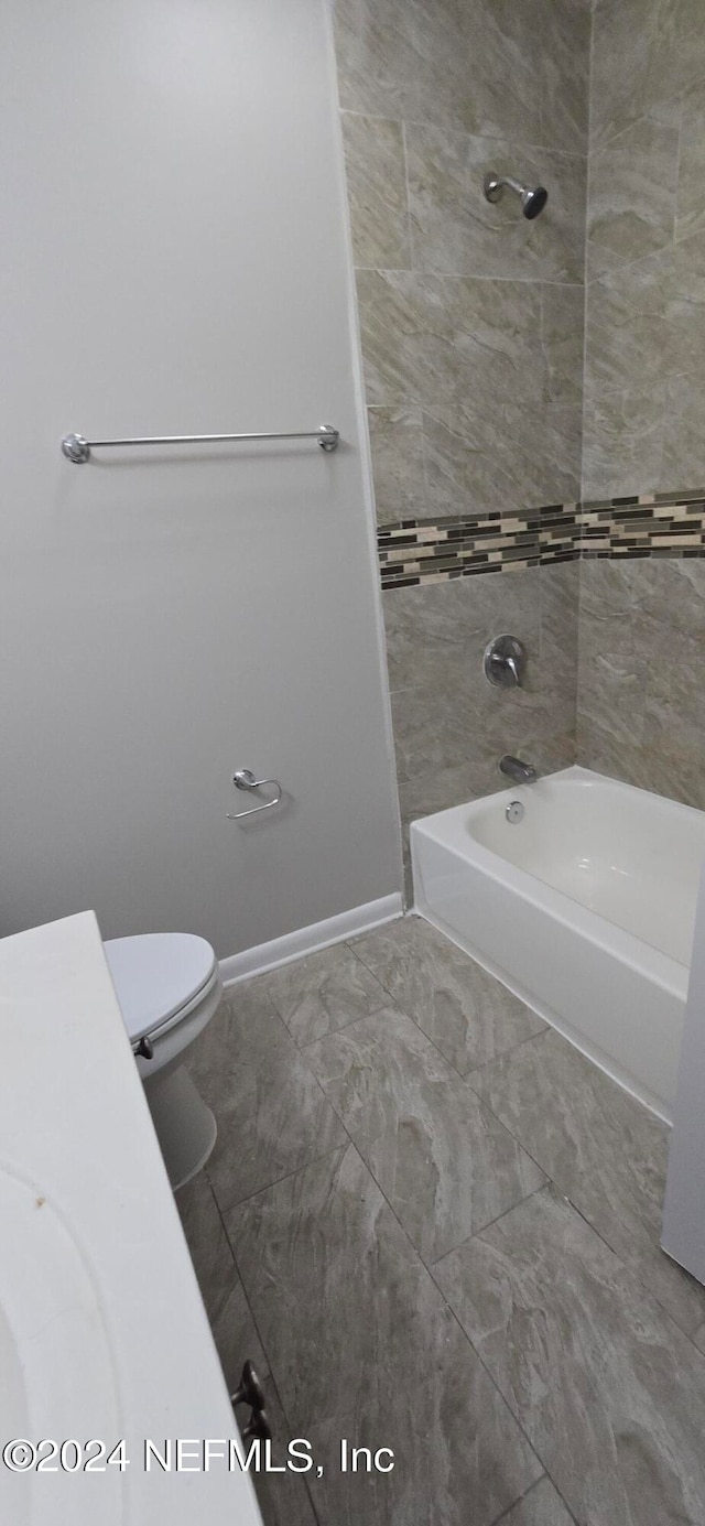 bathroom featuring toilet and tiled shower / bath combo