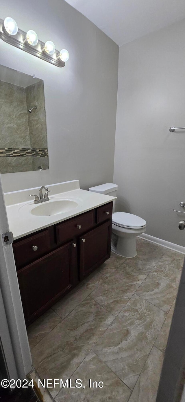 bathroom with vanity, toilet, and tiled shower