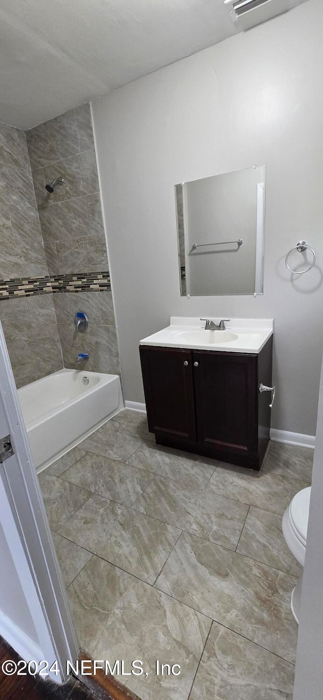 full bathroom featuring vanity, tiled shower / bath combo, and toilet