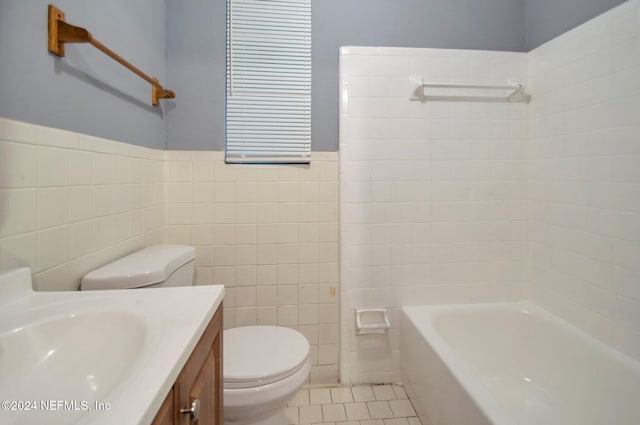 bathroom with toilet, vanity, tile patterned floors, and tile walls