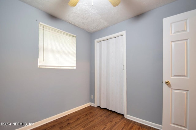 unfurnished bedroom featuring a closet, ceiling fan, a textured ceiling, and dark hardwood / wood-style flooring