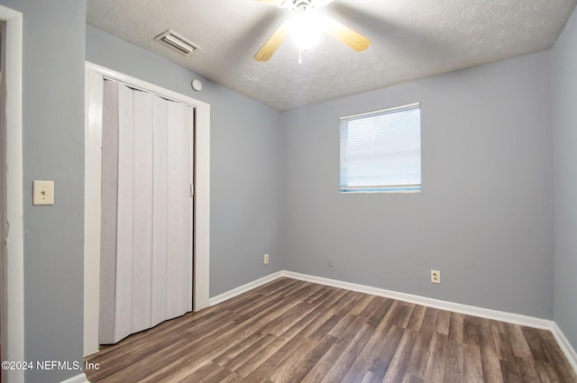 unfurnished bedroom featuring a closet, a textured ceiling, dark wood-type flooring, and ceiling fan