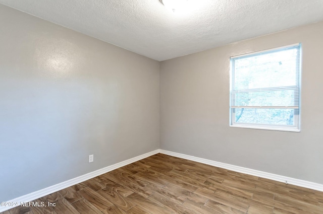 spare room featuring hardwood / wood-style flooring and a textured ceiling