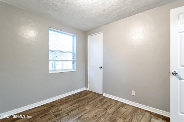 empty room with hardwood / wood-style floors and a textured ceiling