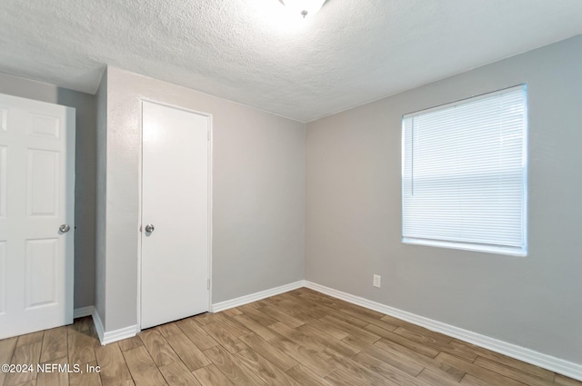 unfurnished room featuring a textured ceiling and light wood-type flooring