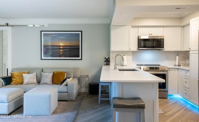 kitchen featuring stainless steel appliances, light hardwood / wood-style flooring, kitchen peninsula, a breakfast bar area, and white cabinets