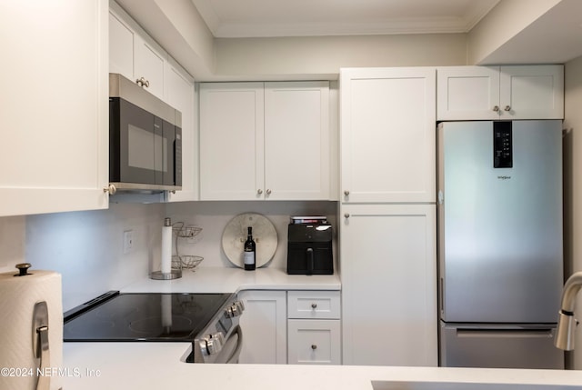 kitchen with white cabinets, ornamental molding, and stainless steel appliances