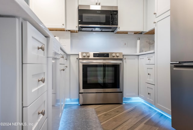 kitchen featuring backsplash, white cabinetry, stainless steel appliances, and light hardwood / wood-style floors