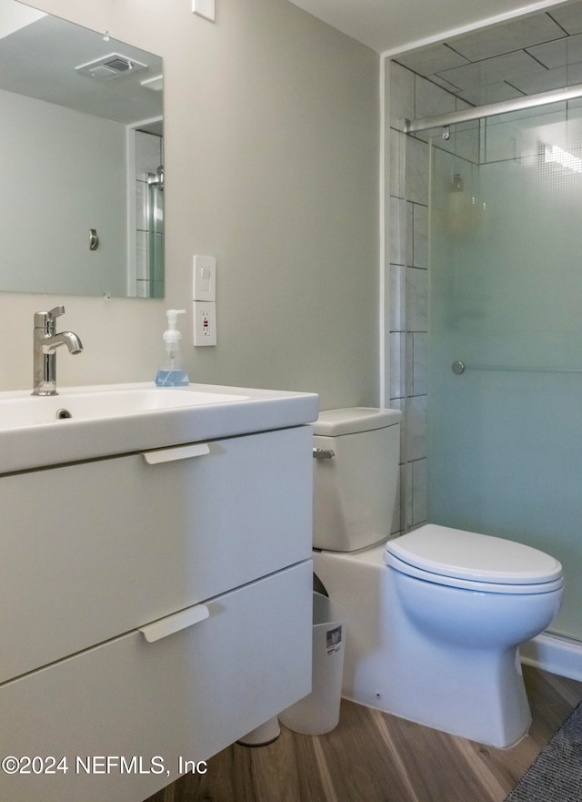 bathroom with an enclosed shower, vanity, toilet, and wood-type flooring