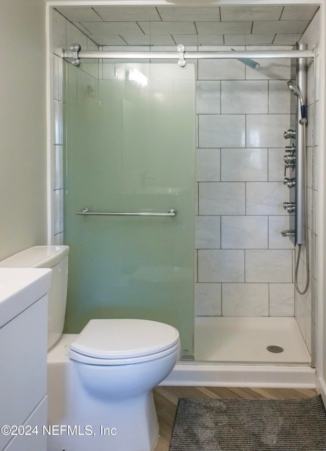 bathroom featuring a shower with door and toilet