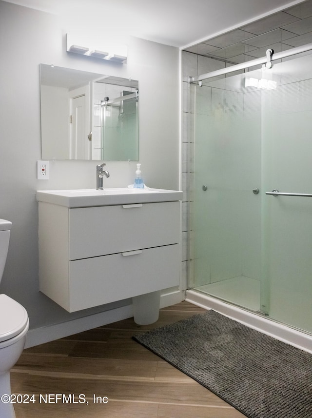 bathroom featuring wood-type flooring, vanity, toilet, and an enclosed shower