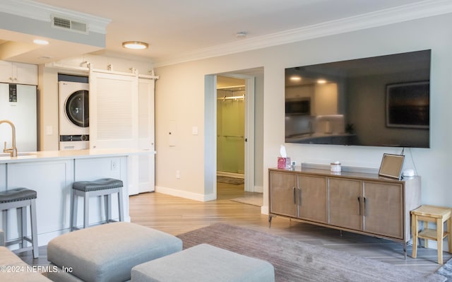 interior space featuring sink, white refrigerator, light hardwood / wood-style floors, stacked washer / drying machine, and ornamental molding