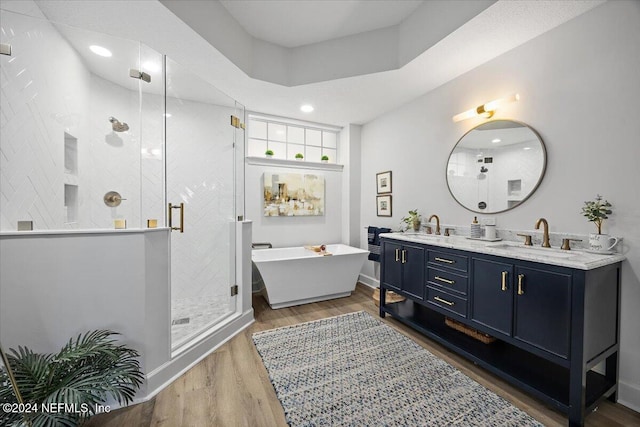 bathroom with a freestanding tub, a stall shower, a sink, and wood finished floors