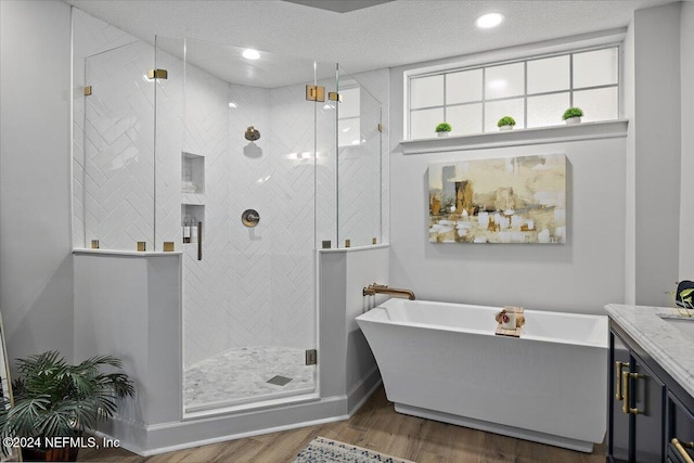 bathroom with a freestanding tub, a stall shower, wood finished floors, and vanity