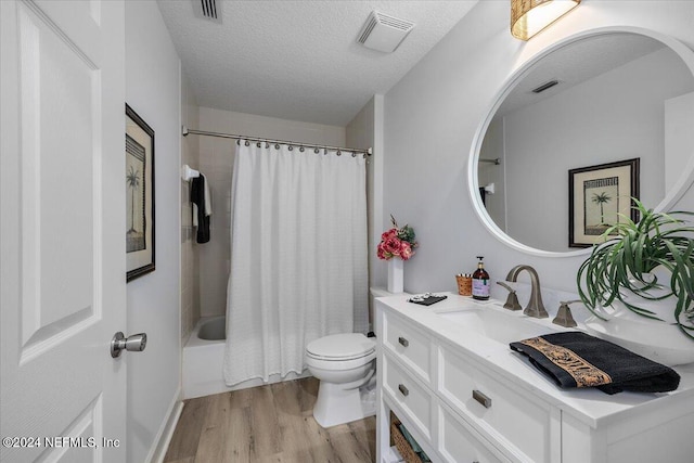 full bath featuring a textured ceiling, toilet, wood finished floors, and visible vents