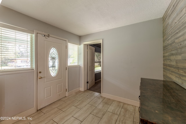 entrance foyer with a textured ceiling, light wood-type flooring, and a healthy amount of sunlight