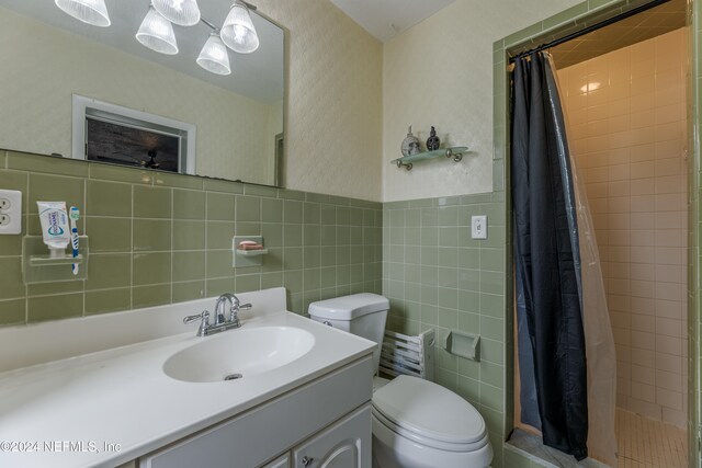 bathroom with a shower with curtain, vanity, toilet, and tile walls