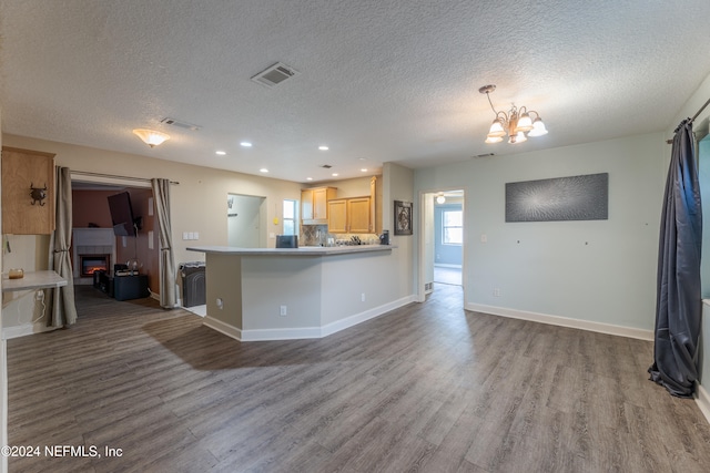 kitchen with a textured ceiling, light brown cabinets, wood-type flooring, and a fireplace