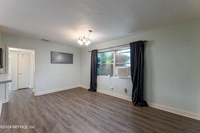 unfurnished room featuring hardwood / wood-style floors, a textured ceiling, cooling unit, and an inviting chandelier