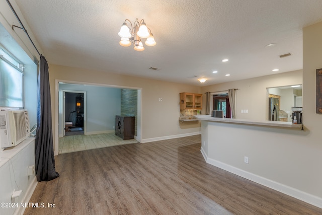 unfurnished living room with a textured ceiling, hardwood / wood-style flooring, and an inviting chandelier