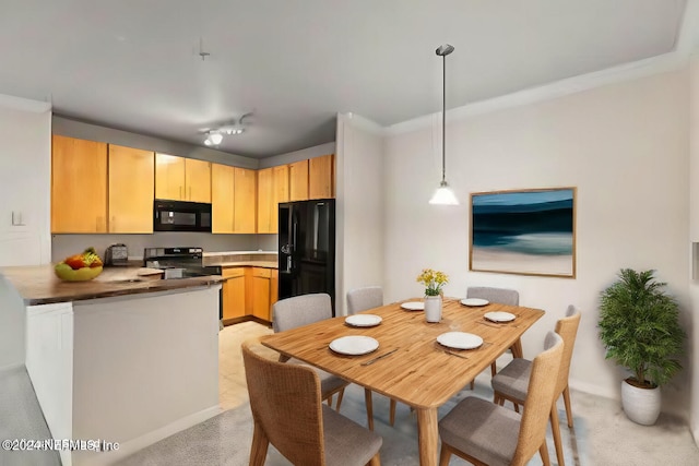 kitchen with crown molding, black appliances, decorative light fixtures, and light brown cabinets