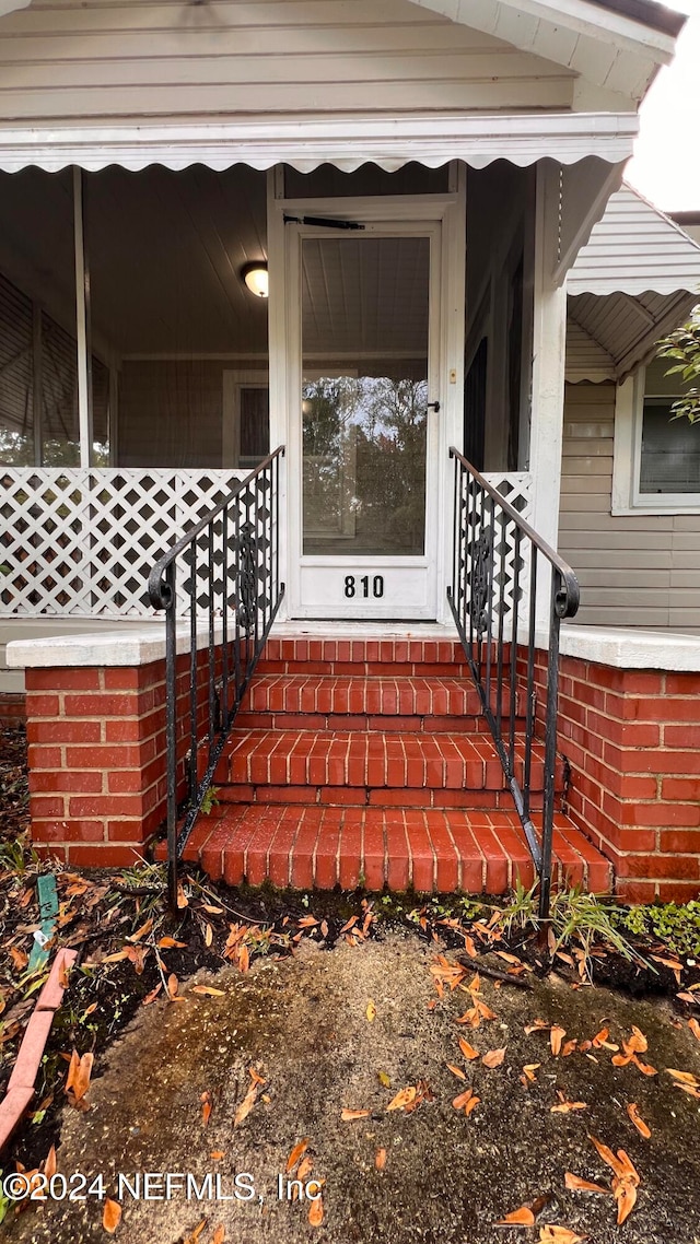 view of exterior entry featuring covered porch