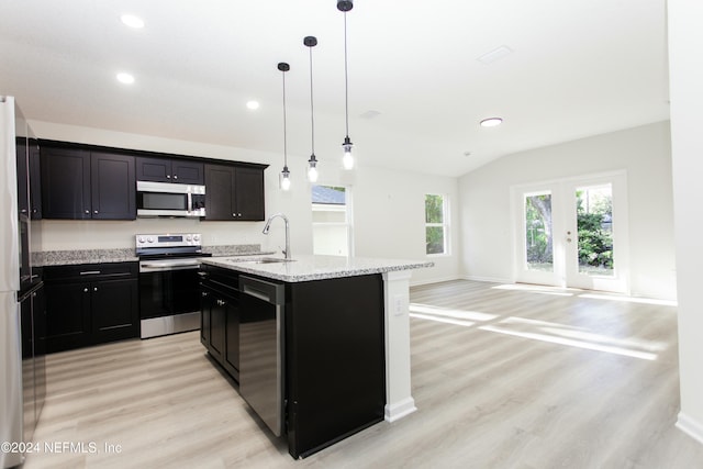 kitchen featuring stainless steel appliances, sink, decorative light fixtures, light hardwood / wood-style floors, and an island with sink