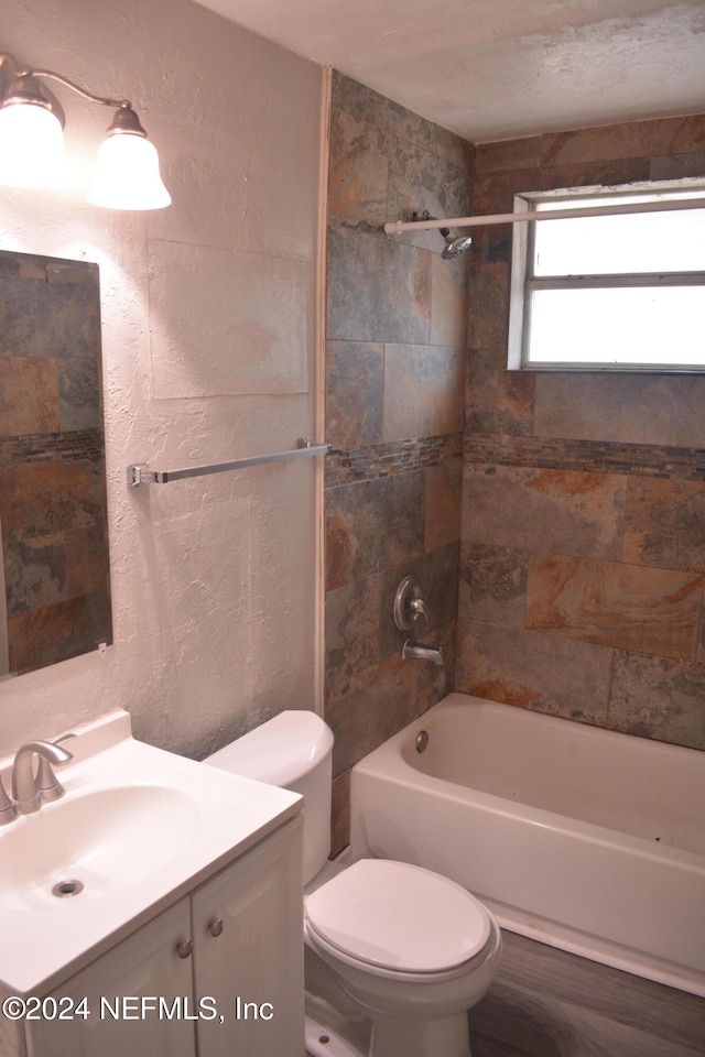 full bathroom with tiled shower / bath, vanity, wood-type flooring, and toilet