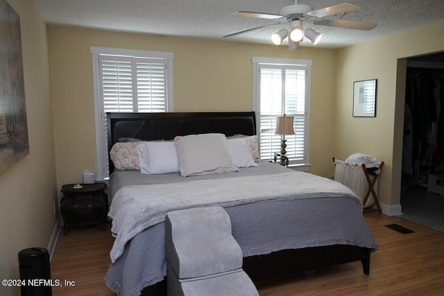 bedroom featuring a textured ceiling, wood-type flooring, and ceiling fan