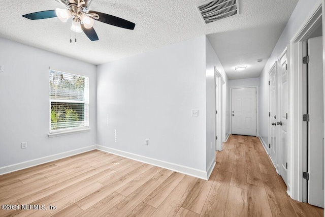 empty room featuring ceiling fan, a textured ceiling, and light hardwood / wood-style flooring