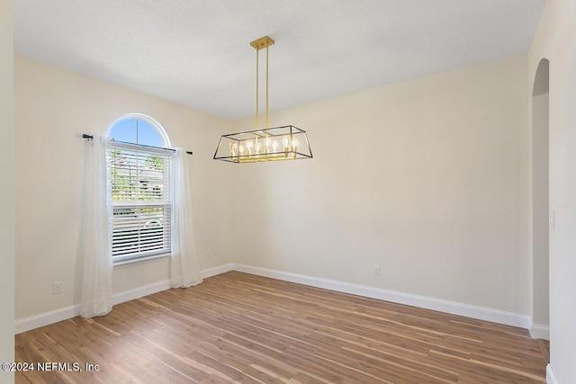 136 Pescado Dr, Saint Augustine, FL 32095 - spare room featuring wood finished floors, baseboards, arched walkways, and a chandelier