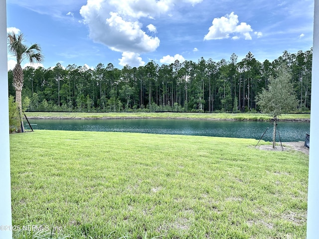 view of yard with a wooded view and a water view