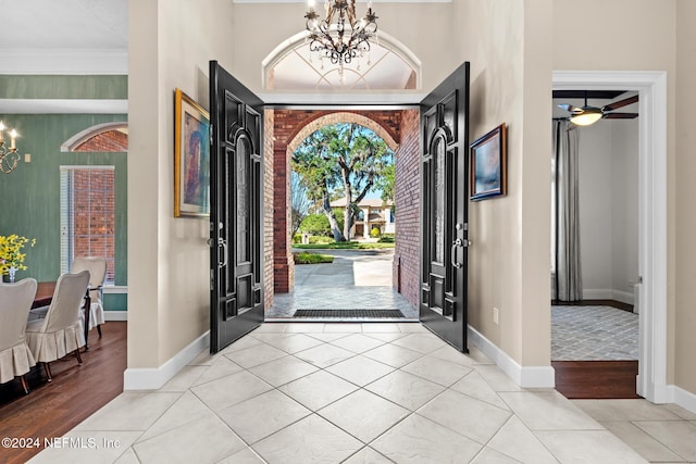 foyer featuring ceiling fan with notable chandelier, light wood-type flooring, and crown molding