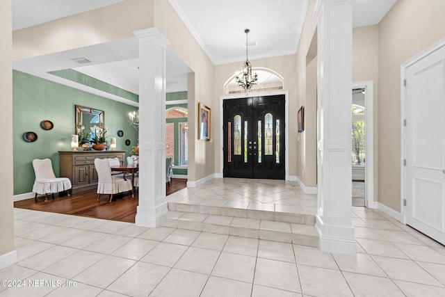 entrance foyer with light tile patterned floors, ornamental molding, a notable chandelier, and ornate columns