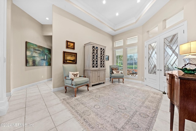 sitting room featuring french doors, ornamental molding, light tile patterned flooring, a raised ceiling, and a high ceiling