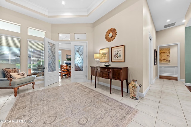 foyer with a high ceiling, light tile patterned floors, and ornamental molding