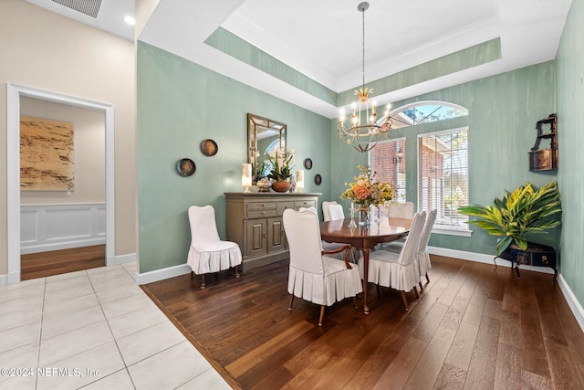 dining area featuring ornamental molding, an inviting chandelier, light hardwood / wood-style floors, and a raised ceiling