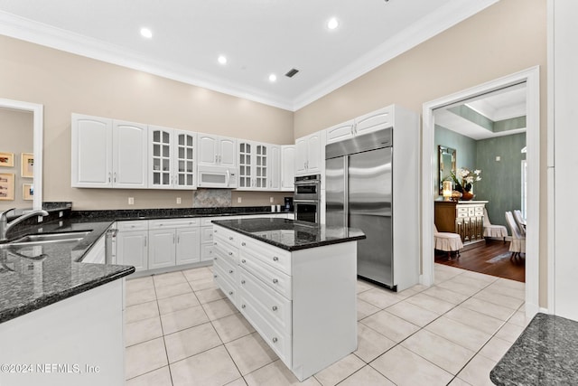 kitchen with stainless steel appliances, light tile patterned flooring, sink, a center island, and white cabinets