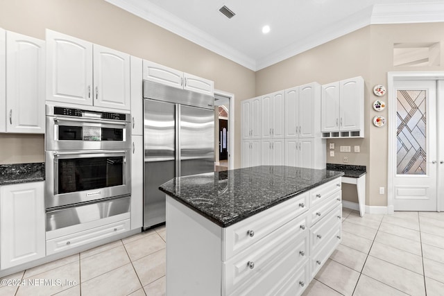 kitchen with stainless steel appliances, white cabinets, light tile patterned floors, and crown molding