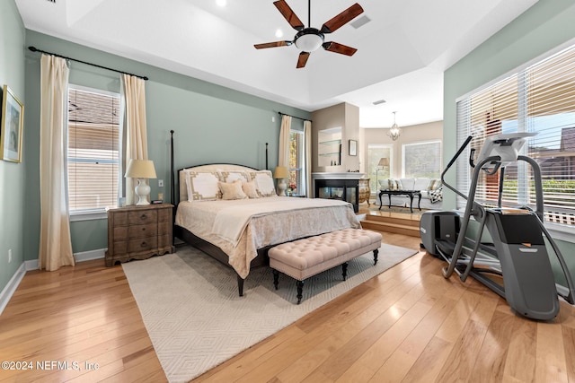 bedroom with light wood-type flooring and ceiling fan with notable chandelier