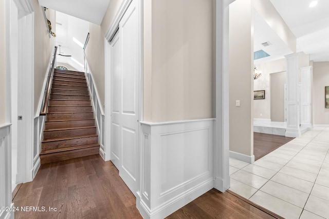 staircase featuring decorative columns and wood-type flooring