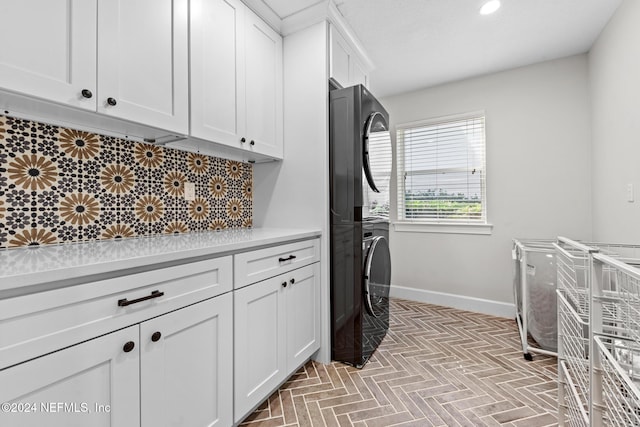 washroom featuring cabinets and stacked washing maching and dryer