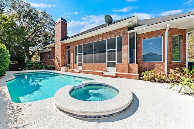 view of swimming pool with an in ground hot tub, a sunroom, and a patio area