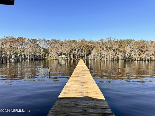 view of dock featuring a water view and a wooded view