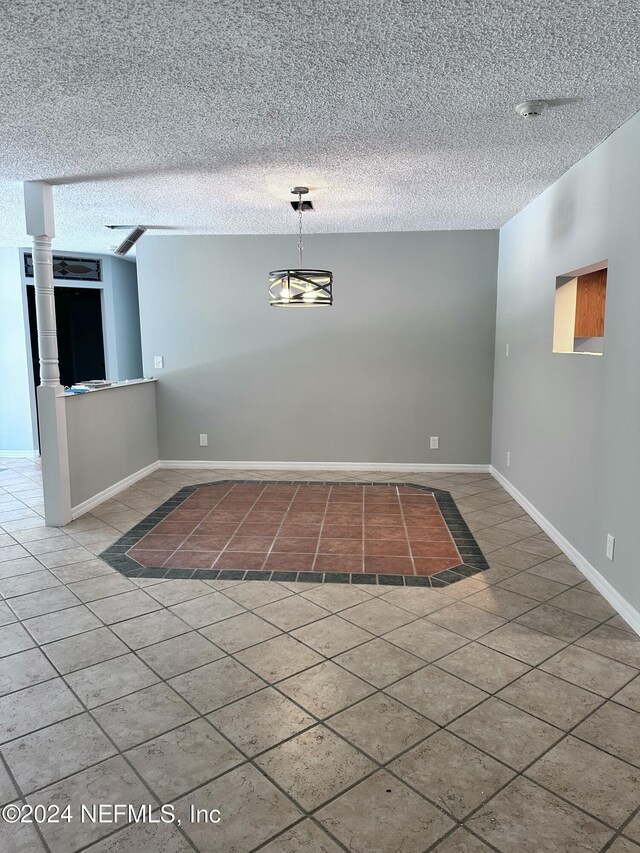 unfurnished dining area featuring a textured ceiling, tile patterned floors, and baseboards