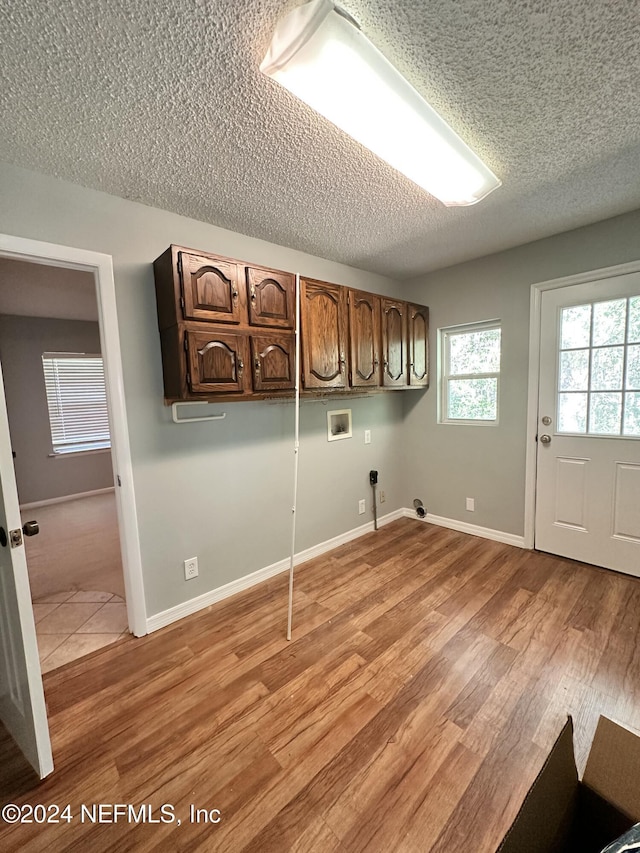 laundry area featuring cabinet space, hookup for a washing machine, a textured ceiling, gas dryer hookup, and light wood-type flooring